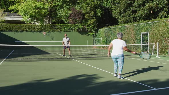 African american senior couple playing tennis on the tennis court on a bright sunny day