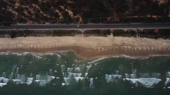 Coastal Vietnam road and sandy beach with ocean waves rolling towards