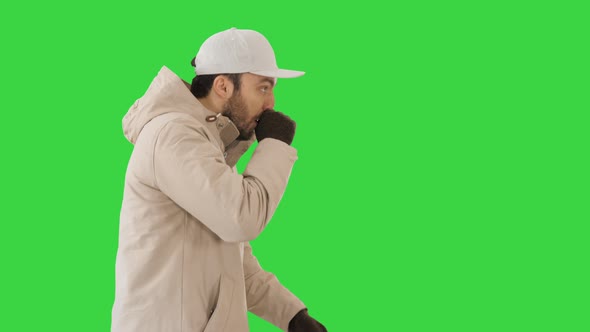 Caucasian Man in a Hat and Coat Coughing Walking on a Green Screen, Chroma Key