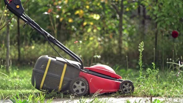 Red lawn mower in the garden. Mowing lawns.