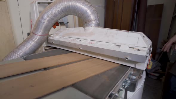 Crop luthier flattening wooden planks on planer in workroom