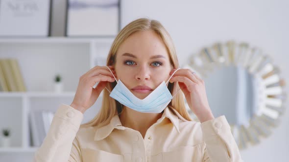 Young attractive woman putting on a medical blue mask. Beautiful girl with medical mask