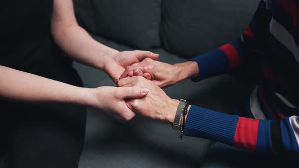 Young Person Holding Hands of an Elderly Woman