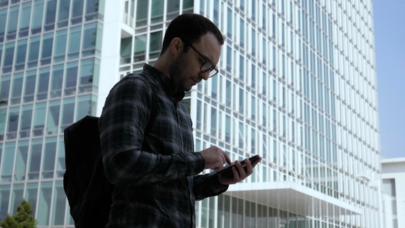 Young Handsome Smart Casual Man Checking Mails on his Smartphone.