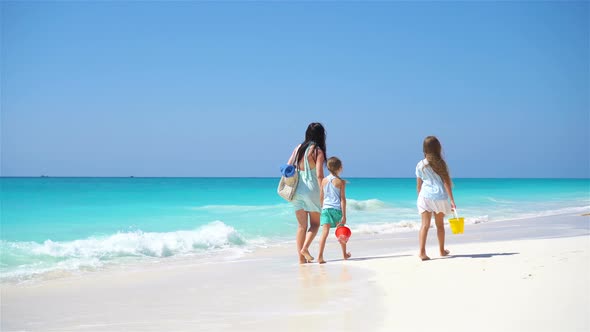 Adorable Little Girls and Young Mother on White Beach