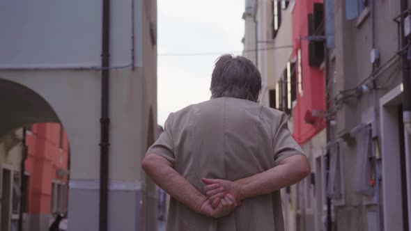 Elderly Stooped Woman Walks Down Narrow Street of Chioggia