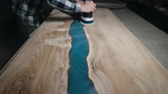 The Carpenter Processes the Surface of a Wooden Tabletop with a Grinder