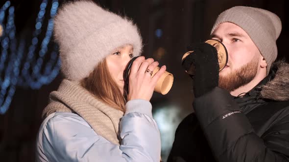 Young Couple in the City During Christmas Drink Hot Coffee