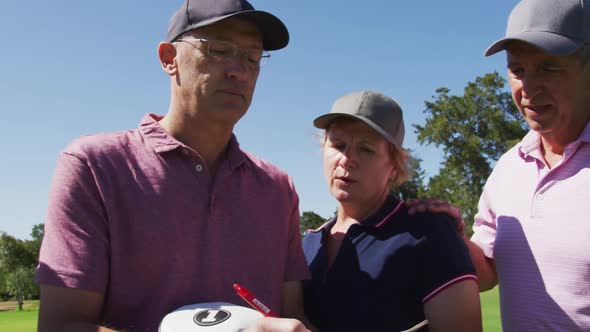 Caucasian senior couple discussing and writing golf score on scorecard at golf course