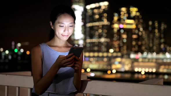 Woman use of mobile phone in Hong Kong city at night 