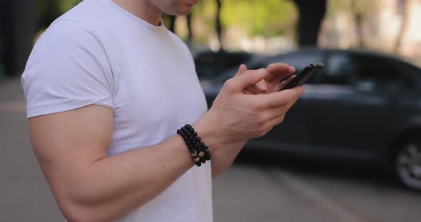 Male Hands Using Mobile Phone in a Summer City