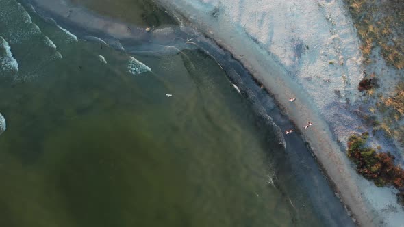 A Topdown Aerial View of a Family Walking Along the Sea at Sunset