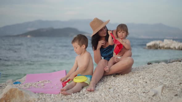 Mom with Children Playing By the Sea on Summer Vacation