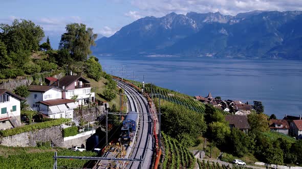 Aerial view following railway tracks under repair. Lake Léman and Mountains in the backgroundGrand