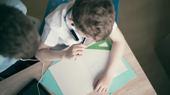 Highangle Shot Children Boys Do School Homework Sitting at a Table in a Notebook Thinking