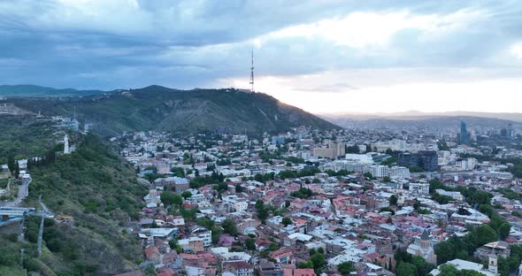 Aerial view of center of Tbilisi under Mtatsminda mountain at sunset. Georgia 2022 summer