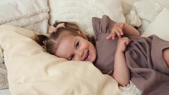 Happy Child Lies on the Bed and Laughs