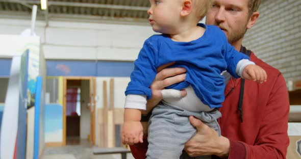 Man holding his son in workshop