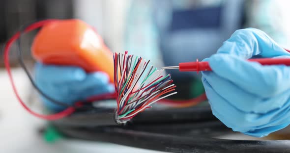 Master Repairman Tests Multicolored Wires From Cable with Tester Closeup