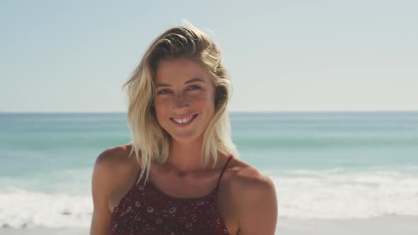 Caucasian woman smiling at beach and looking at camera