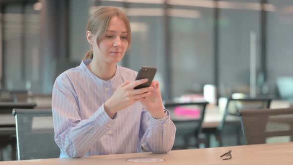 Attractive Young Woman Using Smartphone in Office