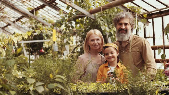 Portrait of Happy Grandparents and Little Girl in Greenhouse Farm