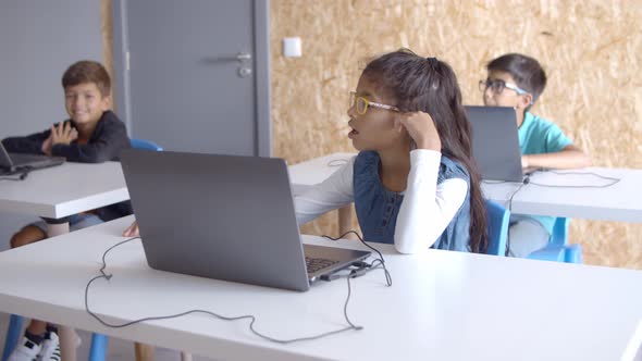 Schoolchildren Sitting at Desks with Laptops