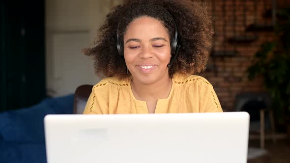 Cheerful AfricanAmerican Woman in Headset Talking Online with Colleagues or Customers