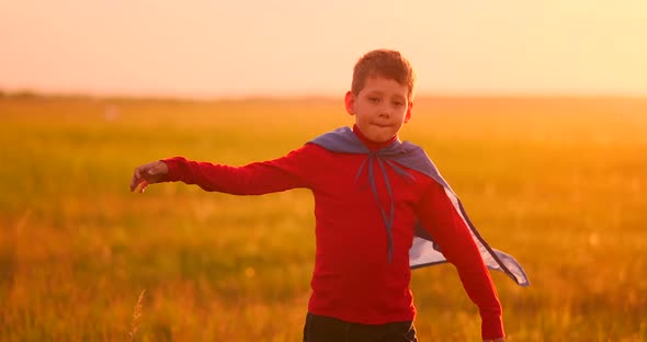 Little Boy Plays and Dreams of a Super Hero at Sunset