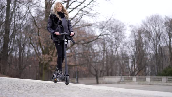 Optimistic Woman Riding Scooter in Park