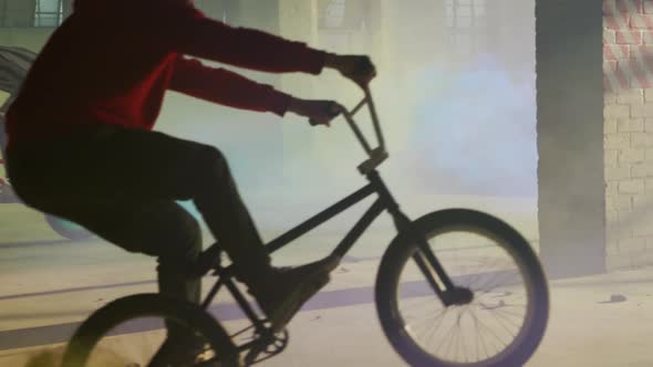 BMX rider in an empty warehouse using smoke grenade