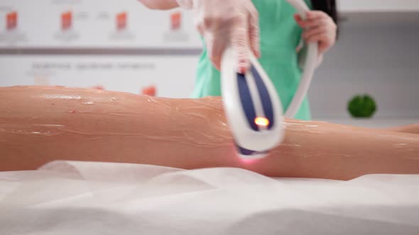 Beautician Woman Makes Procedure for Laser Hair Removal Female Legs Beauty Salon