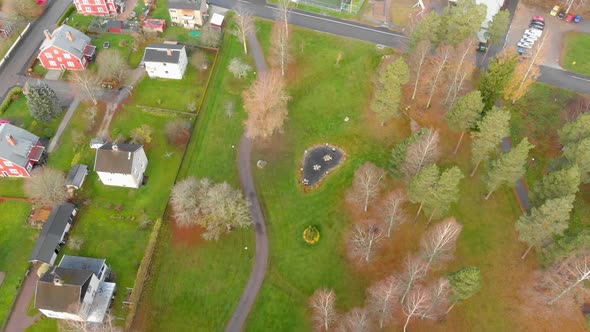 Drone footage flying over a small parque with some redo houses on the left hand side ending up over