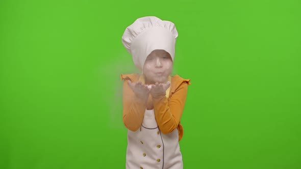 Child Girl Kid Dressed As Professional Cook Chef Blowing Flour From Hands Into Camera on Chroma Key