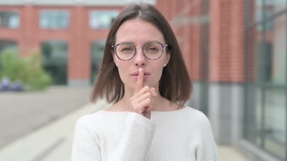 Young Woman Showing Quiet Sign by Finger on Lips