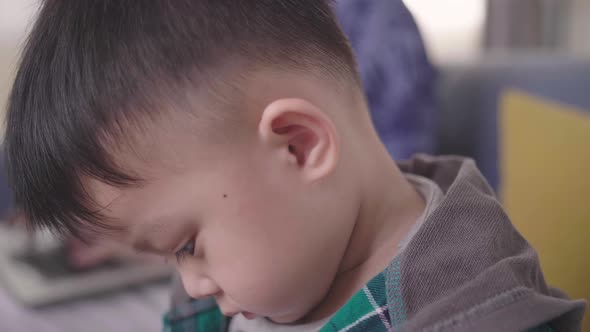 Close Up Boring Boy Using Smartphone While Father Working On Laptop