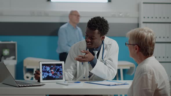 Young Doctor Analyzing Virus Animation on Tablet with Old Woman