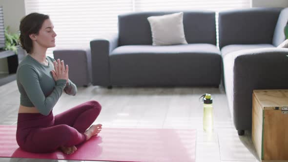 Caucasian woman keeping fit and meditating on yoga mat