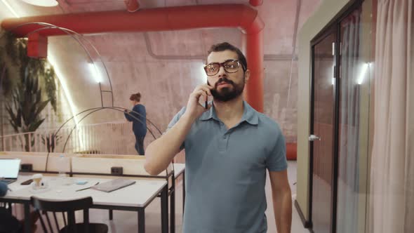 Middle Eastern Man Talking on Phone and Walking in Trendy Office