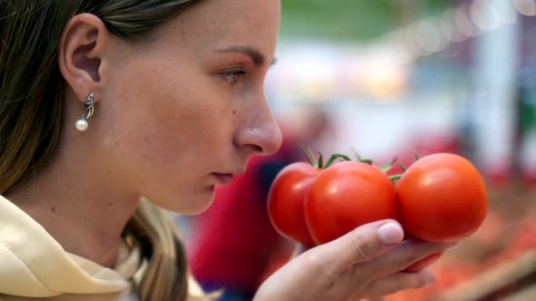 Woman Smelling Tomatoes While Shopping at Market