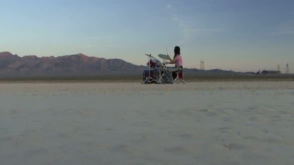 Female playing drums in desert