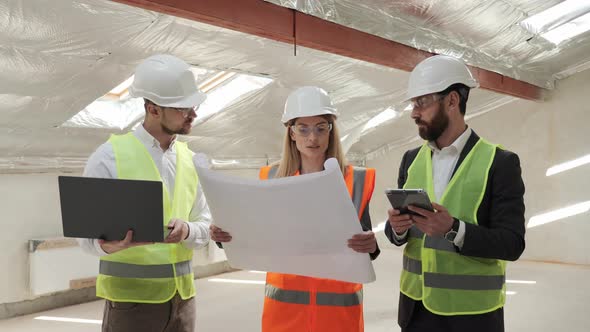 Team of Specialists Use Laptop Tablet Blueprints on Construction Site