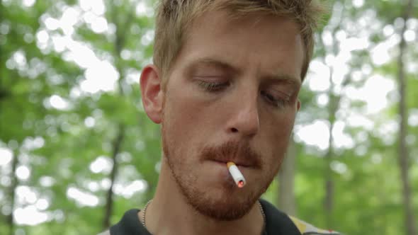 Mid adult man smoking cigarette in forest