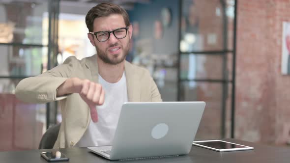 Thumbs Down By Young Man with Laptop