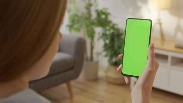 Handheld Camera Back View of Blond Woman Holding Chroma Key Green Screen Smartphone Watching Content