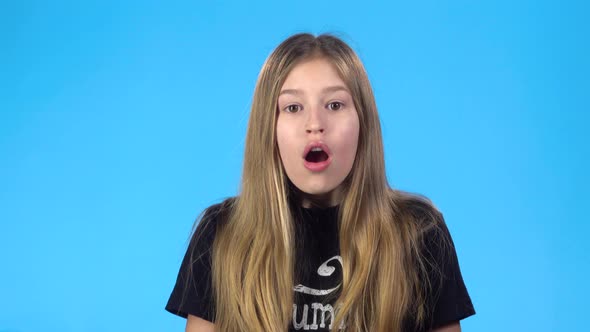 Girl Looking Surprised and Smiling While Posing Against Blue Background