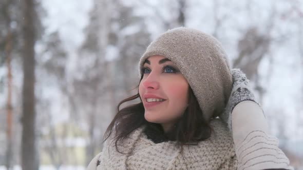 Portrait of a Young Blue-eyed Woman in a Winter Park Who Looks Away and Smiles. Slow Motion