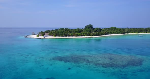 Wide angle flying travel shot of a white sandy paradise beach and blue water background in colourful