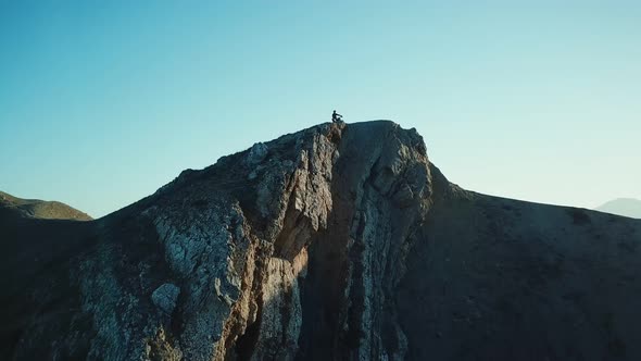 Drone View of Man on Motorbike Extremely Rides Across the Hills with Black Sea on Background 