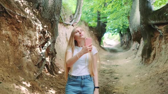 Blonde Young Woman Making Photos on Smartphone in Magical Roots Gorge